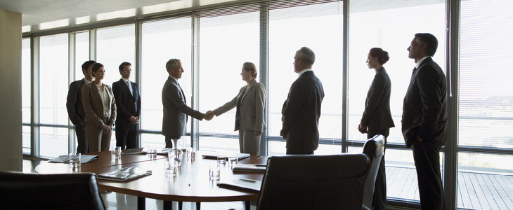 Two business teams shaking hands during a business merger