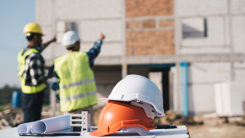 Two construction workers pointing at a construction project