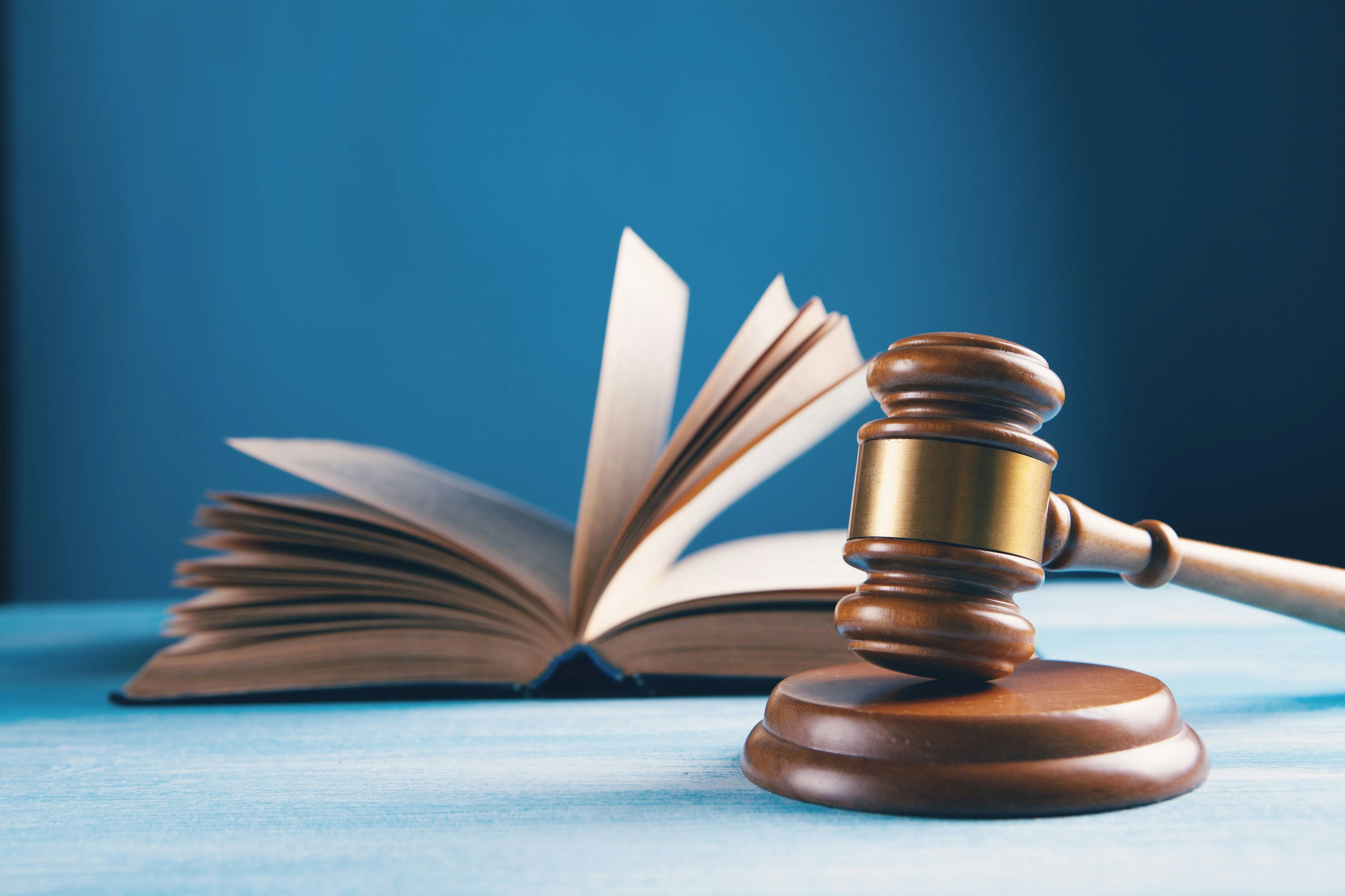 A gavel and law book on a blue background