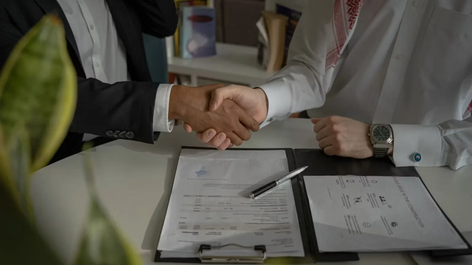 Two people shaking hands over some documents