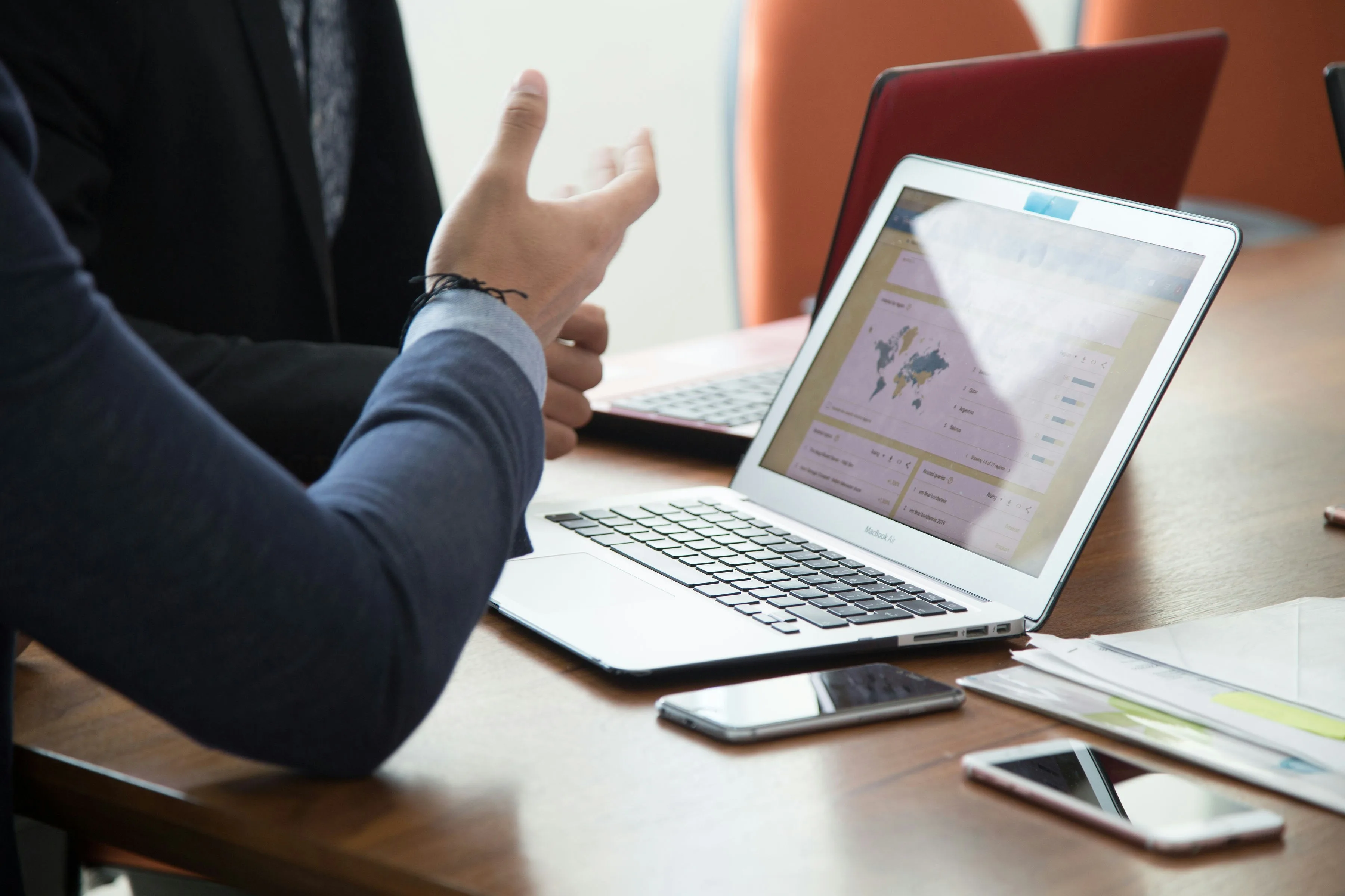 Close up of a laptop with two people talking during a business meeting.