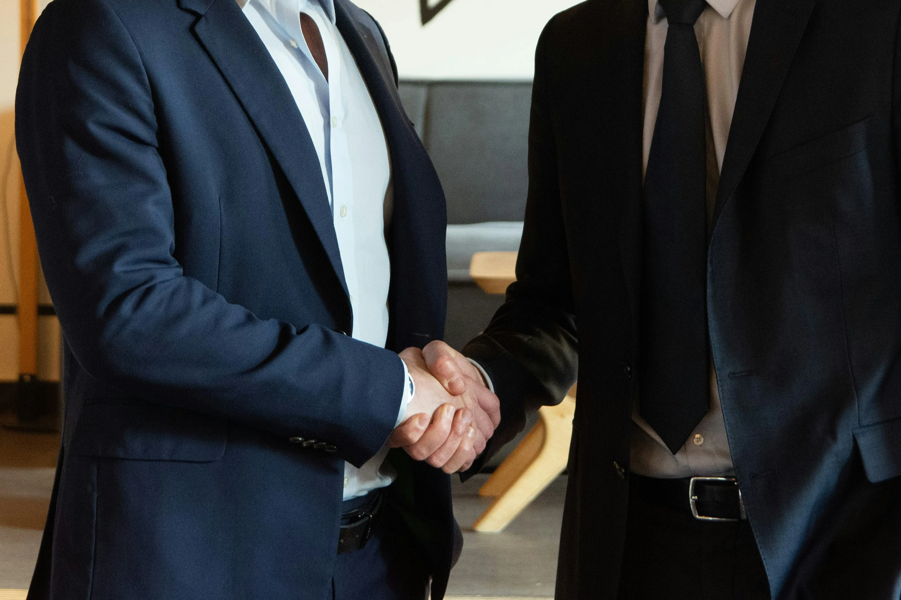 Two men in suits, shaking hands.