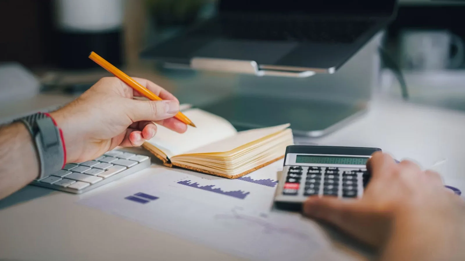 Someone working with a calculator and a notebook.
