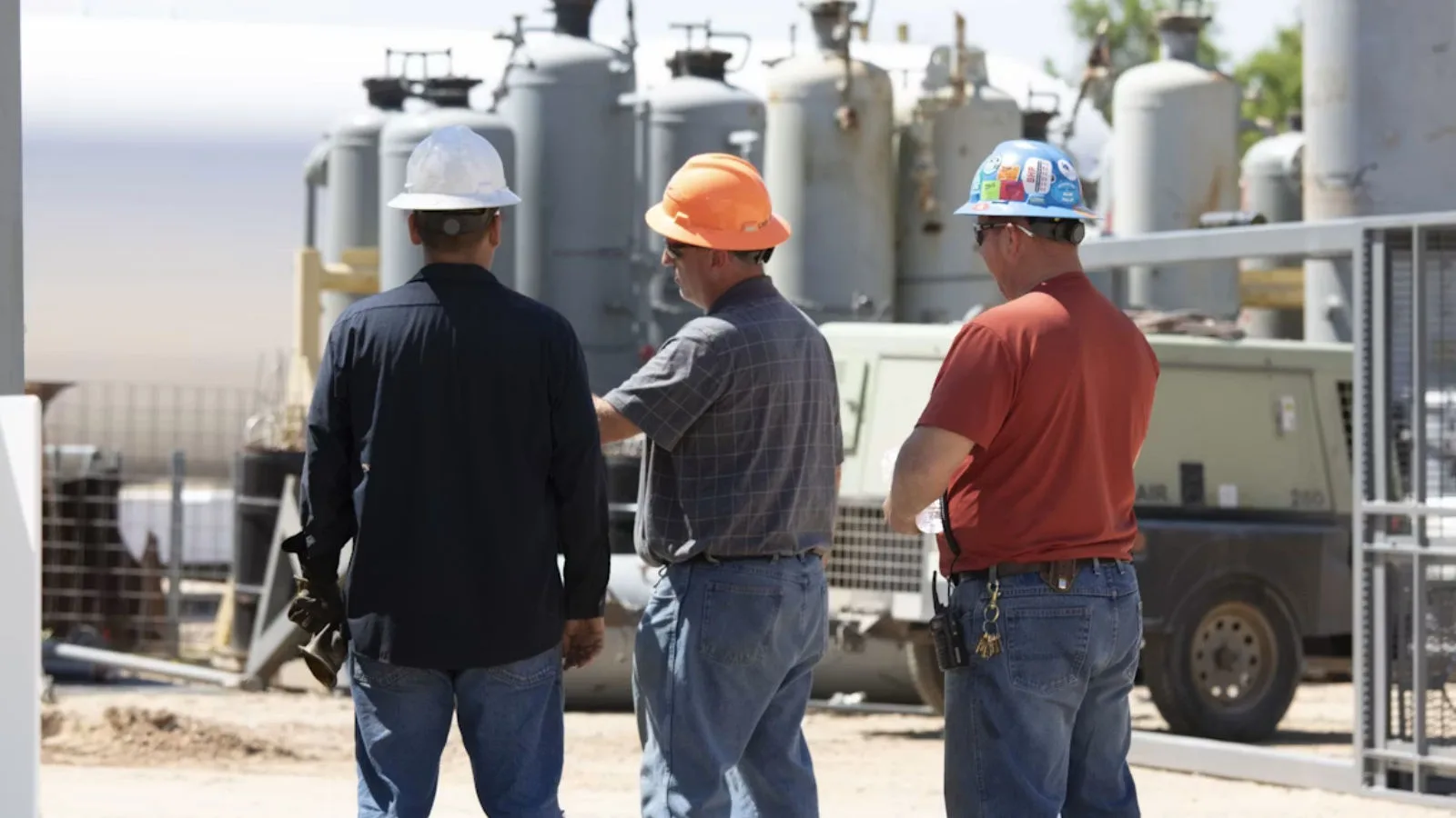 Three men surveying a construction site.