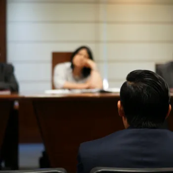 Someone sitting in front of three people defending themselves.