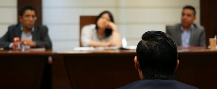 Someone sitting in front of three people defending themselves.
