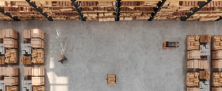 An overhead shot of a warehouse with a pallet jack, high shelves, and stacked boxes.