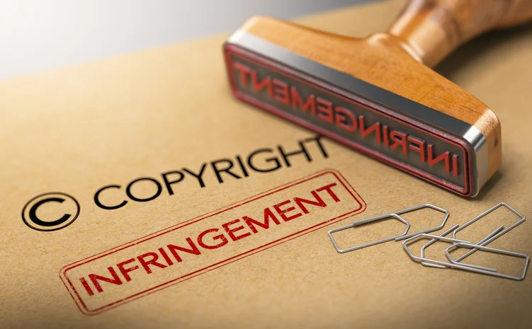 A wooden rubber stamp and paper clips are next to the word "COPYRIGHT" and a red "INFRINGEMENT" stamp.