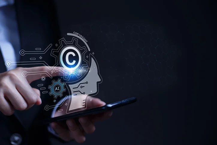 A person holds a phone with a holographic projection of a head showing a copyright symbol inside a gear.