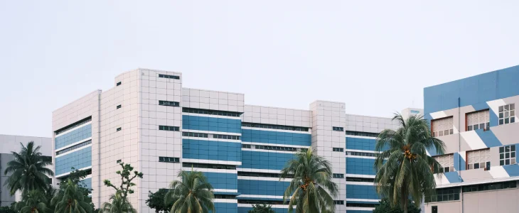 A large, modern building with a blue and white exterior, with palm trees in the foreground.