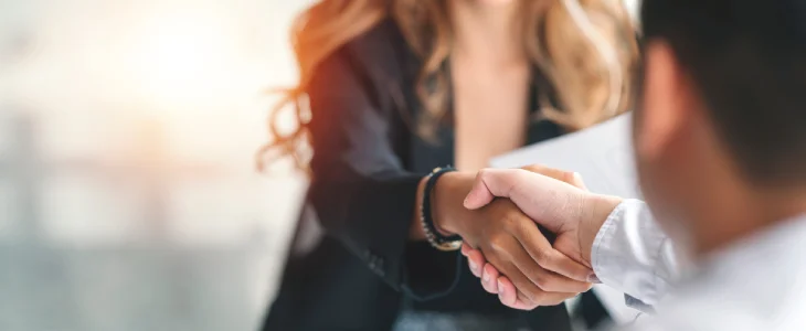 Two people shaking hands in a professional setting.