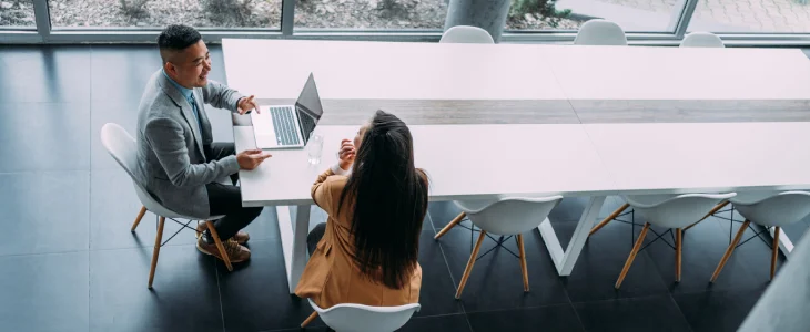 A businessman whispers to a colleague during a meeting.