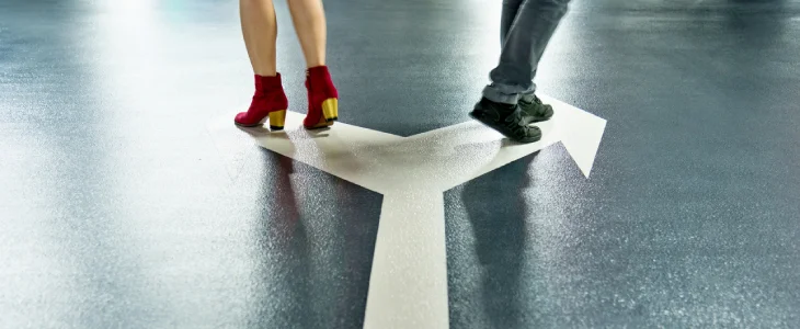 Two people walking on a painted arrow on the ground.