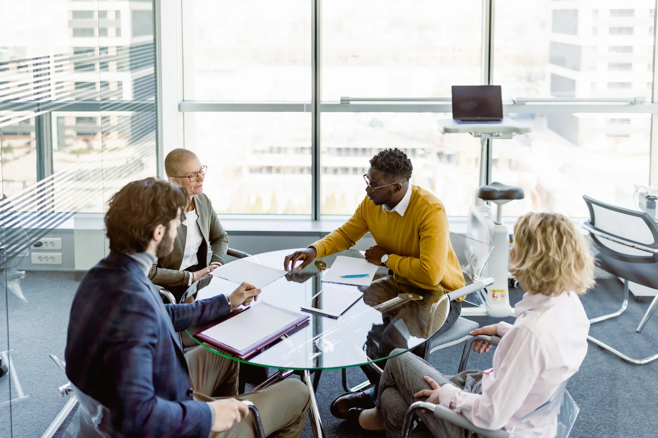"Business team presenting an agreement to clients during an office meeting by a large window."